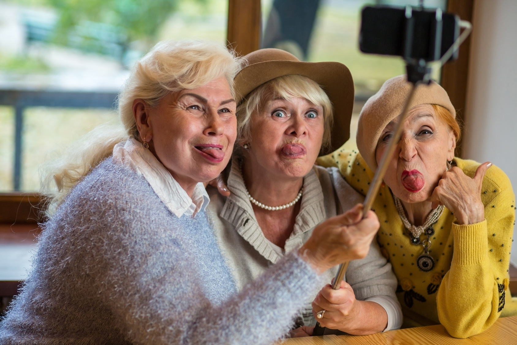 Three ladies taking selfie. Senior women showing tongue. Fooling around like children.