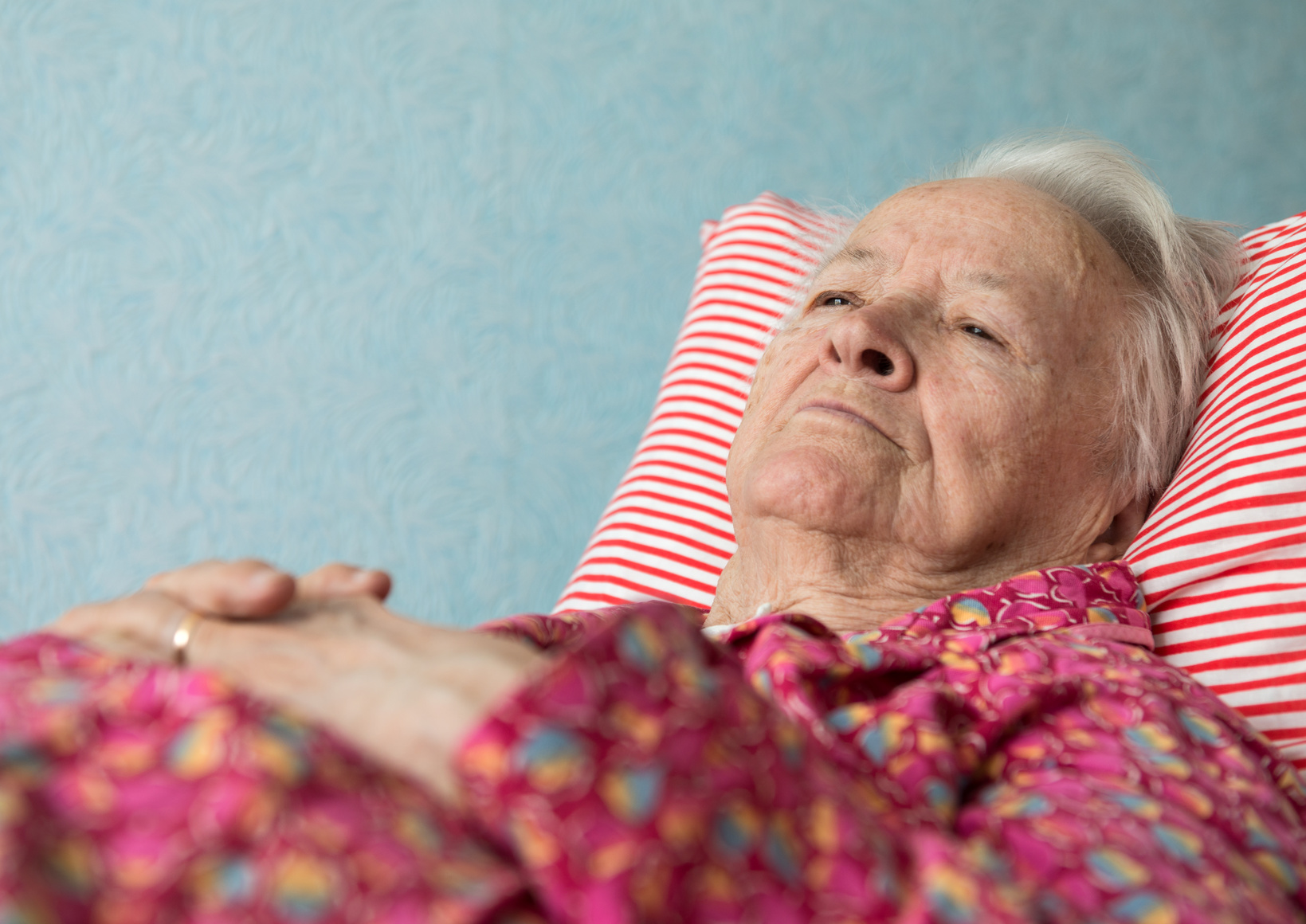 Old sick woman lying in bed at home